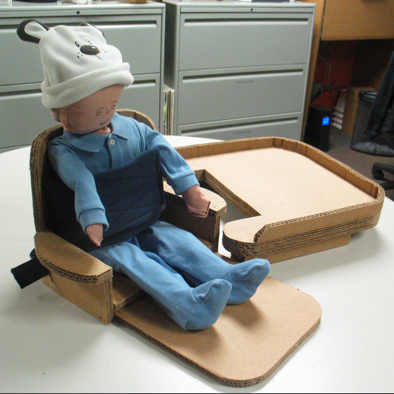 Toddler-sized doll in a cardboard seat